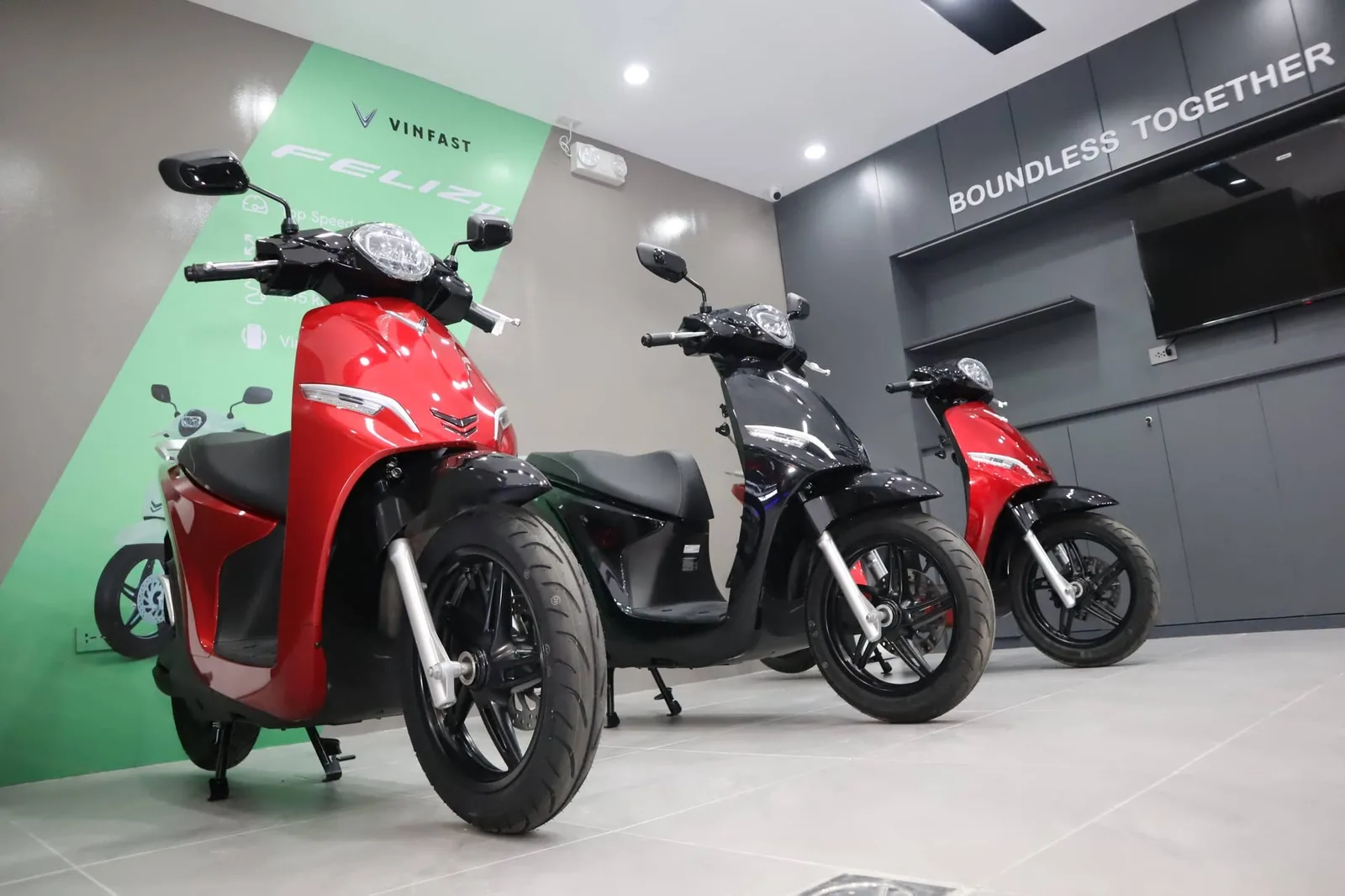 Three VinFast electric scooters on display in a Manila dealership, including a red Feliz II, beneath signage reading Boundless Together.